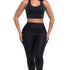 Front full view of a woman with a black sports bra and black leggings with her hands in both side pockets